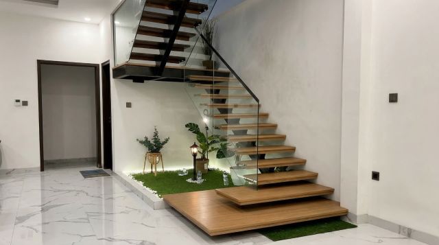 Diseño de una escalera de madera moderna con peldaños de madera oscura, integrada en un espacio minimalista con paredes blancas y una barandilla de cristal.