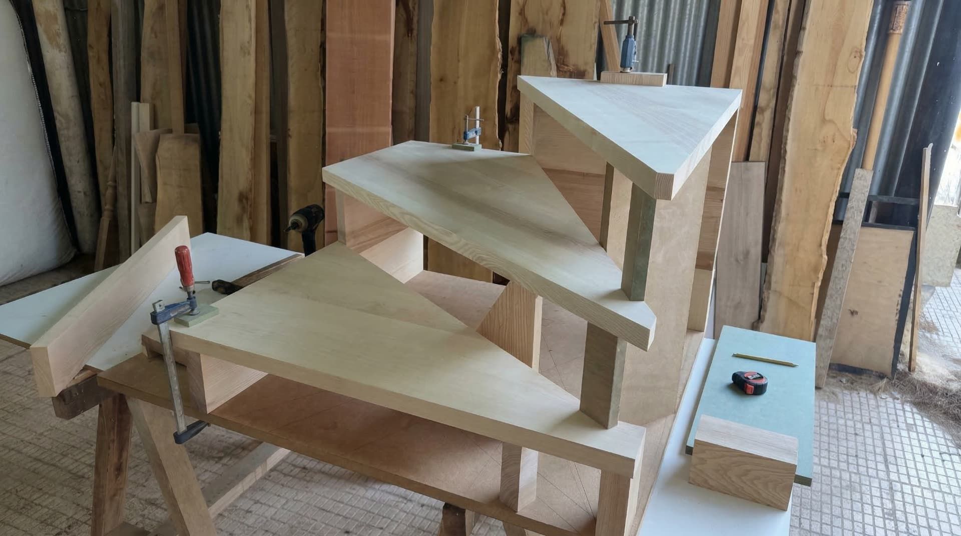 Vista en detalle de la fabricación de escaleras de madera a medida, mostrando peldaños de madera maciza de tono claro.